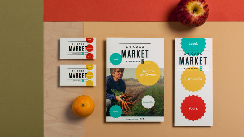 Chicago market business cards, booklet and flyer arranged on a surface with an apple and orange