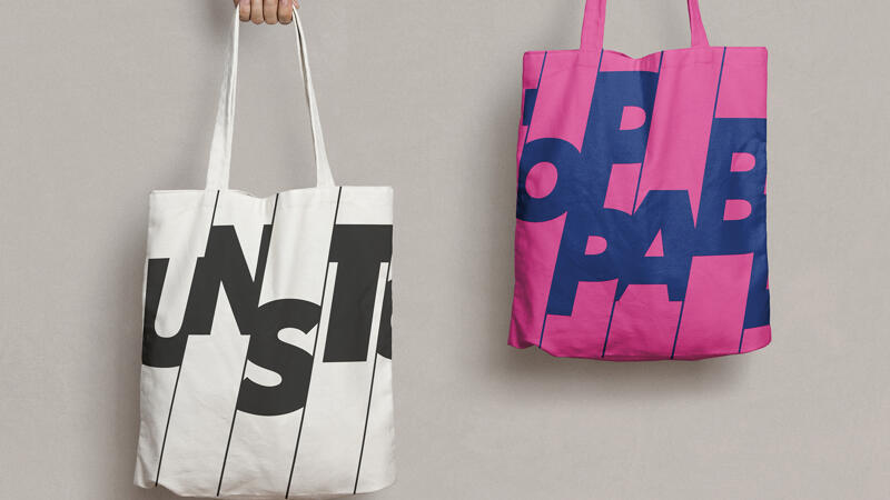 Two tote bags with the cropped unstoppable logo printed on the front. One bag is white one bag is pink