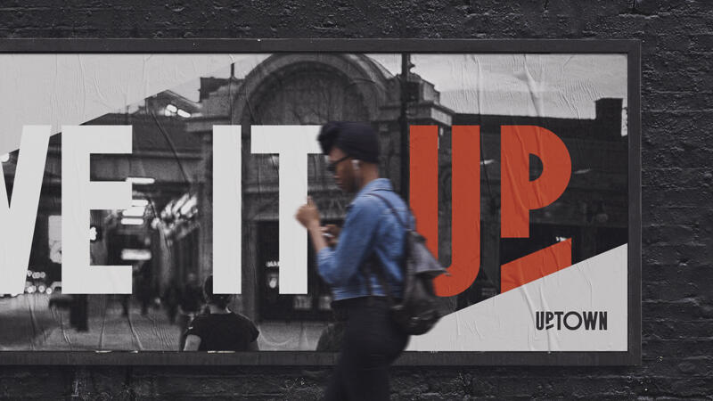 Woman walking in front of billboard featuring Uptown logo and campaign message "Live it Up"
