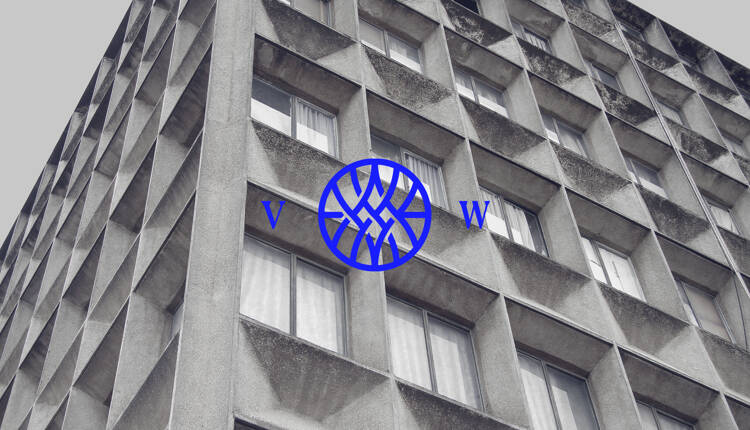 Vested world monogram logo on top of a photograph of a woman working in a factory